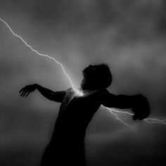 a man is standing in the dark with his arms out as lightning strikes behind him