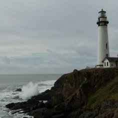 a light house on top of a cliff near the ocean with waves crashing against it