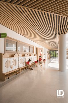 three children are playing in the hallway of a building with wooden slats on the ceiling