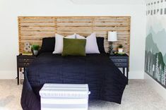 a bedroom with a bed, nightstands and painting on the wall behind it that is made out of wood slats