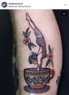 a tattoo on the leg of a person with a cup and flowers in it,