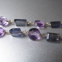 "Small faceted discs of lilac amethyst are paired with faceted tubes of smoky-blue iolite, linked with 14k gold wire into a 22\" chain. The large (20mm), smooth amethyst marble pendant is removable --it clips onto the necklace with the handmade hook clasp. *The modeled necklace is a similar necklace that has sold. Check out Jenco Studios at: www.jencostudio.com and www.facebook.com/jencostudios for work in sterling silver, new work previews, info on upcoming sales and signing up for the Jenco St Fine Jewelry Purple Faceted Jewelry, Elegant Purple Faceted Beads Gemstones, Purple Faceted Fine Jewelry, Faceted Amethyst Gemstones For Jewelry Making, Faceted Blue Amethyst Jewelry, Faceted Amethyst Briolette Gemstones, Blue Faceted Amethyst Jewelry, Purple Briolette Jewelry With Gemstone Accents, Faceted Lavender Briolette Jewelry