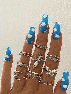 a woman's hand with blue and white nail polish holding five different types of rings