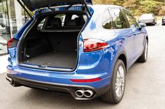 the back end of a blue porsche cayen with its trunk open in a parking lot