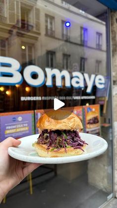 a person holding a plate with a sandwich on it in front of a store window