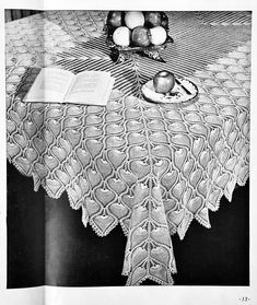 an old photo of a crocheted tablecloth with apples and books on it