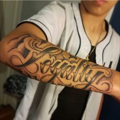 a person with a baseball jersey on and arm that has the word faith tattooed on it