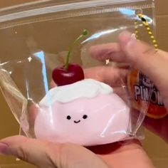 a person holding a small plastic object with a cherry on it's head in a clear bag