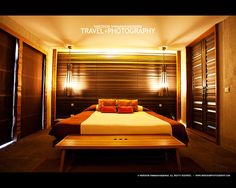 a bed sitting in the middle of a bedroom next to a wooden table with pillows on it