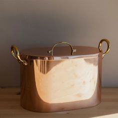 a large metal pot sitting on top of a wooden table next to a white wall