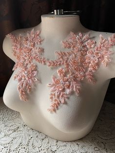 a white mannequin with pink flowers on it's chest and lace around the neck