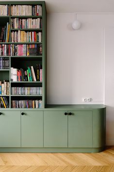 a green bookcase filled with lots of books on top of a hard wood floor