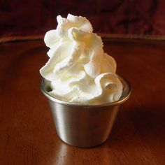 a cup filled with whipped cream on top of a wooden table