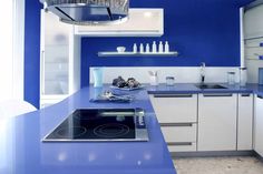 a kitchen with blue counter tops and white cupboards, including a stove top oven