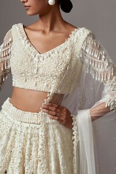 Ivory lehenga featuring embroidered floral motifs in scalloped patterns, highlighted by pearls ,crystals and sequins. Comes with matching blouse highlighted by pearl and crystal cluster patterns. Paired with embellished dupatta. - Aza Fashions Fitted V-neck Wedding Sets, Elegant Lehenga With Resham Embroidery And V-neck, Festive White V-neck Sets, Wedding Set With Pallu In V-neck Shape, Wedding Set With Pallu And V-neck, Wedding Sets With Pallu And V-neck, V-neck Lehenga With Resham Embroidery For Wedding, V-neck Lehenga With Dupatta For Wedding, Bollywood Style V-neck Choli For Wedding