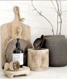 a bottle of soap sitting on top of a wooden stand next to pots and spoons