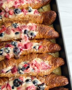 several croissants with blueberries, strawberries and cream cheese on them