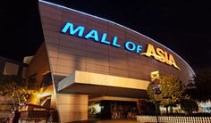 the entrance to a mall at night with people standing outside and lights on in the background