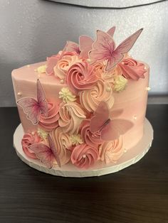 a pink cake decorated with butterflies and flowers