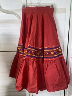 Handmade VTG Red Mexican Circle Skirt Bottom Ribbons Folkloric Jalisco Skirt XS Wide waist band with zipper and hook and eye closure. Two tiers. Bottom of the top tier has multi colored zig zag ribbons and embroidered thick ribbon. Opens to full skirt. Great for dancing and parties. Must be little and Small. Measurements taken laying flat Waist 11.5" Length 29.5" No flaws to note except for a small hole which is hard to find when worn. Could be fixed. A very uniquely made skirt. A true one of a Red Bohemian Cotton Skirt, Bohemian Red Flared Skirt Bottoms, Bohemian Red Cotton Skirt, Bohemian Red Flared Skirt, Traditional Red Cotton Skirt, Red Embroidered Skirt For Festival, Fitted Red Skirt For Festival, Red Mini Skirt For Festival, Red Lined Skirt For Festival