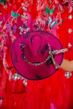 This stylish fuchsia rancher hat adds a touch of whimsy to any outfit. It features a beaded band encased in a dozen butterflies, for a unique and eye-catching look. Perfect for adding a little personality to your wardrobe. This hat is one-of-a-kind, created by our owner Stephanie. This hat is ONE OF A KIND. To receive item quicker, expedited shipping is available at checkout. Bohemian Pink Hat Band For Kentucky Derby, Pink Fedora With Flat Brim For Party, Pink Flat Brim Fedora For Party, Handmade Purple Party Hat, Pink Fedora For Party, Pink Fedora For Kentucky Derby Party, Whimsical Fedora For Kentucky Derby Festival, Pink Hat For Kentucky Derby Festival, Adjustable Hats For Kentucky Derby And Carnival