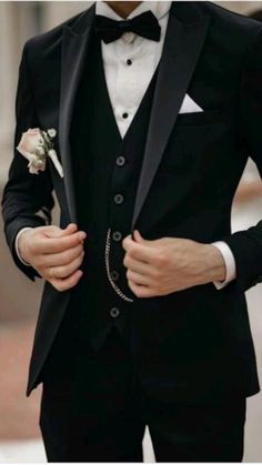 a man in a tuxedo is wearing a white rose boutonniere