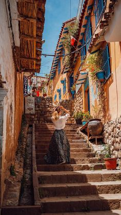 a woman is walking down some steps in an alley