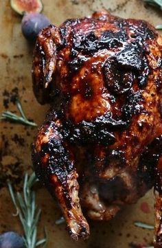 a close up of a cooked chicken on a table with figs and blueberries