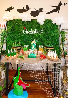 a table topped with lots of desserts and balloons in front of a green wall