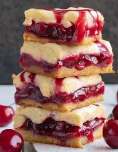 cherry cheesecake bars stacked on top of each other with cherries in the background