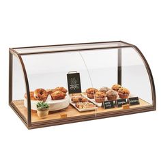 a bakery display case filled with muffins and other pastries on top of a wooden cutting board