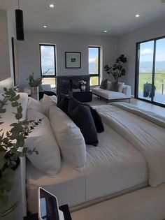 a living room filled with white furniture and large windows overlooking the ocean on a sunny day