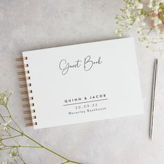 a wedding guest book next to a pen and flowers