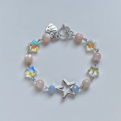 A handmade bracelet ✨ ✿ Made with mother of Pearl, glass crystal beads, glass beads, and metal accents ✿ Cream, iridescent clear, ice blue, and silver ✿ Toggle Clasp Charm Necklace Ideas Bead, Metal Beads Bracelet, Cute Star Bracelet, Clear Blue Glasses, Glass Bead Charm Bracelet, Handmade Breclates, Metal Bracelet Ideas, Cute Charms For Bracelets, Star Beads Bracelet