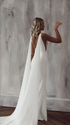 a woman in a white wedding dress is standing with her back turned to the camera