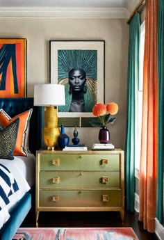 a bedroom decorated in gold and blue with art on the wall, bedding, and curtains