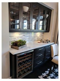 a kitchen with black cabinets and white marble counter tops, wine rack in the center