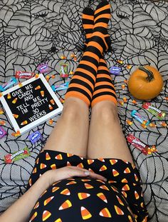 a woman in striped socks laying on top of a bed next to an orange pumpkin