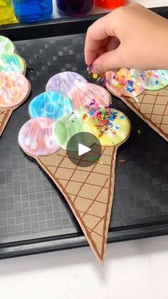 two ice cream cones are being made with colored paper and sprinkles on them