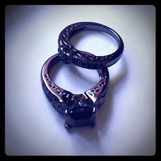 two silver rings sitting on top of each other with black stones in the middle,