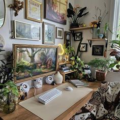 a home office with plants and pictures on the wall, including a computer keyboard sitting on top of a wooden desk