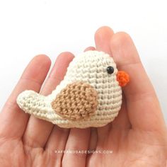 a small crocheted bird sitting on top of someone's hand