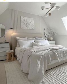 a white bed sitting under a window next to a dresser and lamp in a bedroom