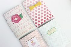 four small notebooks are lined up on a white surface with pink and green polka dots