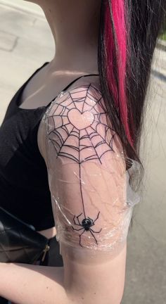 a woman with pink hair has a spider web tattoo on her arm