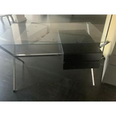 a glass table with metal legs on the floor