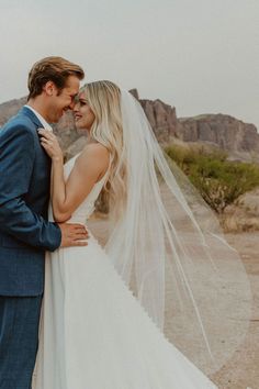 a bride and groom standing together in the desert