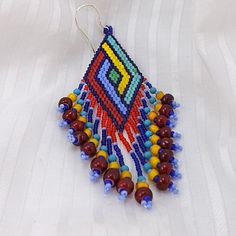 a pair of beaded earrings on a white cloth with red, yellow and blue beads