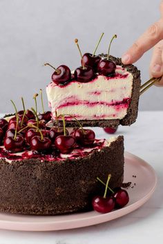 a piece of cake with cherries on it being held by someone's hand