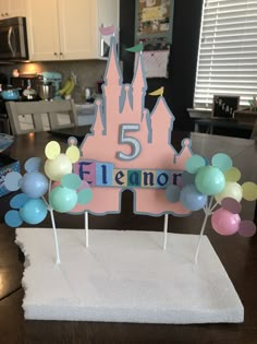 a birthday cake with balloons and a castle topper that says 5 is for flanner